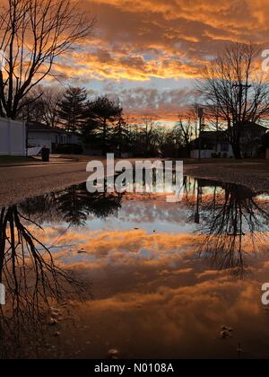 Merrick, New York, USA. Januar 24, 2019. Reflexion der bunten Winter Sonnenuntergang füllt große Pfütze auf der Straße nach der Überschwemmung am Südufer von suburban Long Island entfernt. Credit: aparry/StockimoNews/Alamy leben Nachrichten Stockfoto