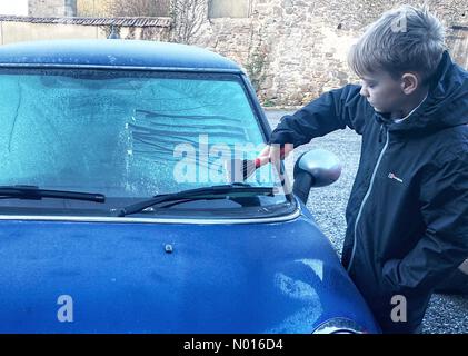 UK Wetter: Jack Porter kratzt Eis von einer gefrorenen Autoscheibe vor der Schule in frostigen Doddiscombsleigh, Devon, Großbritannien. 11th. Februar 2022. Credit nidpor/Alamy Live News Credit: Nidpor/StockimoNews/Alamy Live News Stockfoto