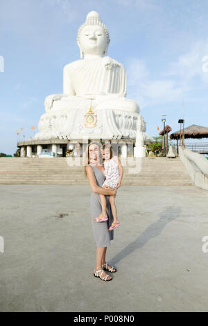 Jungen kaukasischen Mutter steht mit der kleinen Tochter in der Nähe von konkreten Statue von Buddha in Phuket. Stockfoto