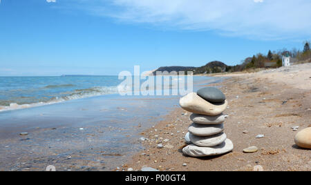 Ein Stapel von Felsen an Empire Beach am Lake Michigan sind abgebildet mit der Sleeping Bear Dunes National Lakeshore in der Ferne. Stockfoto