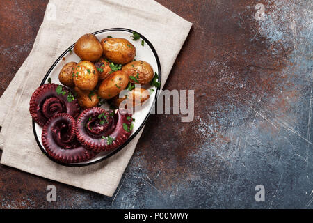 Gegrillter Tintenfisch mit kleinen Kartoffeln mit Kräutern und Gewürzen. Ansicht von oben mit Platz für Ihren Text Stockfoto
