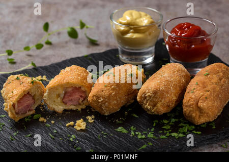 Frischen Teig Kugeln mit Wurst und Käse auf einem dunklen Schiefer gefüllt Stockfoto