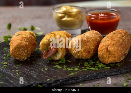 Frischen Teig Kugeln mit Wurst und Käse auf einem dunklen Schiefer aufgefüllt Ansicht schließen Stockfoto