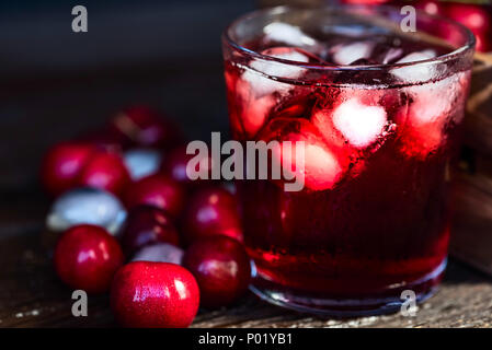 Frische Kirschen Eiswürfel und Kirschsaft auf Holz Stockfoto