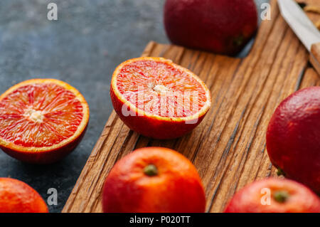 Ganze und aufgeschnittene frische reife Blutorangen auf einem Holzbrett. Nahaufnahme Stockfoto