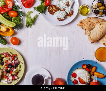 Griechische Vorspeisen - Krapfen von Zucchini mit Tzatziki Sauce, Griechischer Salat, Joghurt mit frischem Obst und Nüsse, Oliven, Gemüse und Kräuter, Ansicht von oben, c Stockfoto