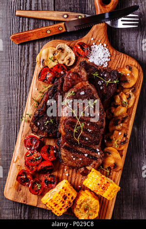 Rindersteaks mit gegrillten Tomaten, Champignons und Mais, Ansicht von oben. Stockfoto