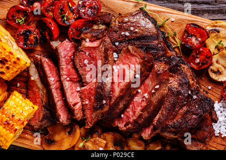 Rindersteaks mit gegrillten Tomaten, Champignons und Mais, Ansicht von oben. Stockfoto