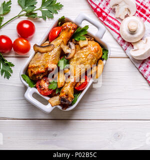 Hähnchenschenkel gebraten mit Champignons und Tomaten, Ansicht von oben. Stockfoto