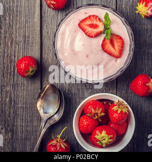 Hausgemachte Joghurt mit frischen Erdbeeren auf einer hölzernen Hintergrund, Ansicht von oben. Stockfoto