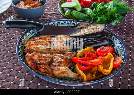 Gegrillte Tabak Huhn mit Sauce auf einer Steinplatte mit Bulgarischen gebratene Paprika aubergine Zucchini und Knoblauch. Köstliches Abendessen. Natürliche Heimat - Cooke Stockfoto