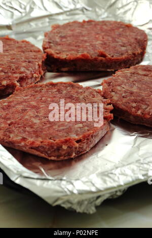 Rohes Rindfleisch Burger auf einer Folie abgedeckt Backblech fertig gekocht zu werden Stockfoto