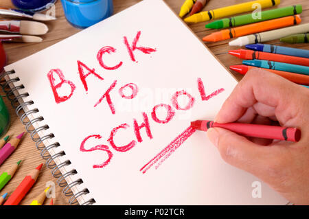 Die Worte zurück in die Schule, auf ein weißes Notebook mit verschiedenen Farben, Kreiden und Stifte geschrieben. Selektive konzentrieren. Stockfoto