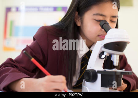 Studentin in Uniform mit Mikroskop in Wissenschaft Kategorie Stockfoto