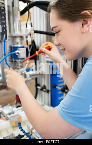 Weiblichen Lehrling Techniker arbeiten an Maschine im Werk Stockfoto