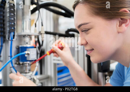 Weiblichen Lehrling Techniker arbeiten an Maschine im Werk Stockfoto