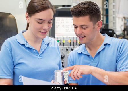 Techniker anweisen weiblichen Lehrling über den Einsatz der CNC-Maschine Stockfoto