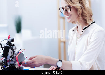 Angenehme schöne Frau, ihr Smartphone auf den Roboter Stockfoto