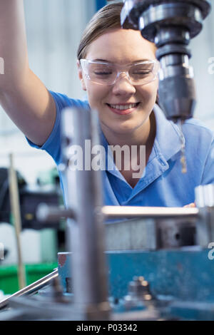 Weibliche Auszubildende mit der Bohrmaschine in der Factory Stockfoto