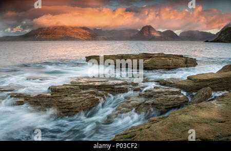 Elgol, Skye, Schottland. Suchen von elgol auf die Cullins. Wenn die Wellen sanft über die Steine, die Sonne leuchtet in der Ferne Cullins Ridge. Stockfoto