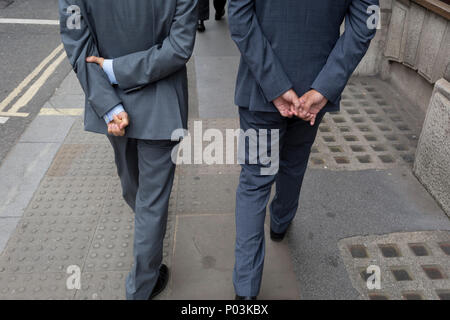 Zwei Geschäftsleute Spaziergang entlang einer Straße, die beide mit gefalteten Händen hinter dem Rücken, in der City von London - Financial District in der Hauptstadt, am 4. Juni 2018 in London, England. Stockfoto