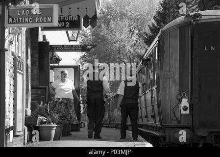 Schwarz-weiße Nostalgie am Bahnhof Hampton Loade, Severn Valley Heritage Railway, Großbritannien. Die Teeleiterin begrüßt den Bahnhofsmeister, den Vorarbeiter und die Wache im Zug! Stockfoto