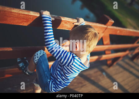 kleinen Jungen über den Zaun klettern Stockfoto