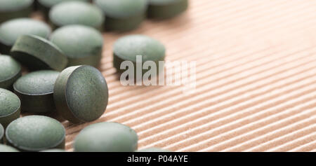 Detail der viele organische Spirulina Tabletten mit geringer Tiefenschärfe über Karton Hintergrund. Stockfoto