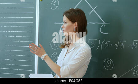 Hübsche Lehrerin im Gespräch mit den Schülern im Klassenzimmer. Stockfoto