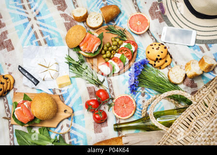 Picknick auf dem Rasen mit Korb, Sandwiches, Obst, Erdbeere, Salat und Oliven. Ansicht von oben Stockfoto