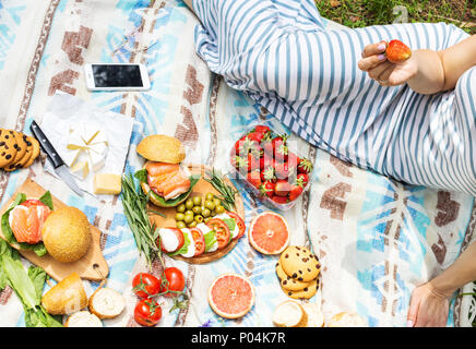 Picknick auf dem Rasen mit Korb, Sandwiches, Obst, Erdbeere, Salat und Oliven Stockfoto