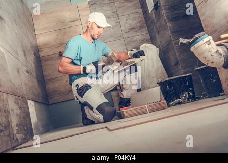 Bad Renovieren von Männern. Kaukasische Keramikfliesen Installer während seiner Arbeitszeit. Holz, wie z.b. Fliesen. Stockfoto