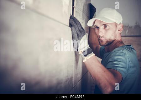 Kaukasische Auftragnehmer in seinem 30s Installation von Wänden im Bad Fliesen. Präzise Installation,. Stockfoto