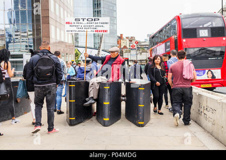 Mann mittleren Alters, der religiösen Spoiler mit einem Plakat, sitzt auf den Anti-terror-Fahrzeug Barrieren auf die London Bridge durch Borough Market, London SE1 Stockfoto