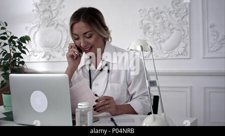 Weibliche Arzt am Telefon zu sprechen und Suchen von Dokumenten. Stockfoto