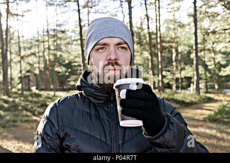 Close up Portrait der kaukasischen bärtiger Mann mit Take away Tasse Kaffee Wanderungen in Wald und genießt die Privatsphäre. Eine Pause Konzept Stockfoto