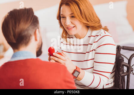 Ja sagen. Fröhliche ungültige Frau halten Lächeln auf dem Gesicht, während ihr Mann auf der Suche Stockfoto