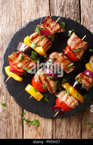 Saftig gegrillte Fleischspieße Schweinefilet mit Tomaten, Paprika, Zwiebeln und Auberginen close-up auf einer Schiefertafel Platte auf einen Tisch. Vertikal oben Ansicht von oben Stockfoto