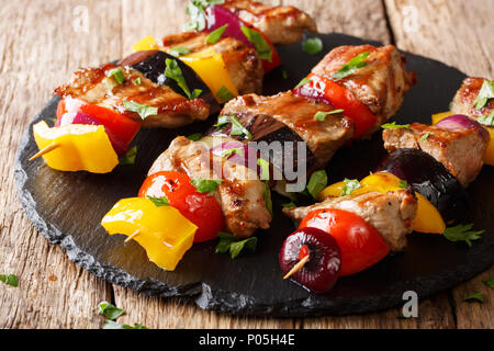 Leckere heiße Grill Shish Kebab aus Schweinefleisch mit Gemüse, serviert auf einem Schiefer Platte close-up auf einem Tisch. Horizontale Stockfoto