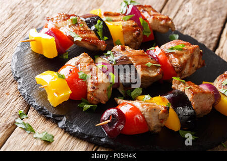 Hausgemachte gegrillte Fleischspieße vom Schwein mit Gemüse, auf einer Schiefertafel platte Nahaufnahme auf dem Tisch serviert. Horizontale Stockfoto