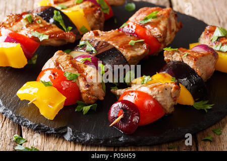 Saftig gegrillte Fleischspieße Schweinefilet mit Tomaten, Paprika, Zwiebeln und Auberginen close-up auf einer Schiefertafel Platte auf einem Tisch. Horizontale Stockfoto