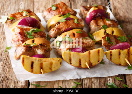 Rustikale saftigen Döner Schweinefilet mit Äpfeln und roten Zwiebeln close-up auf Pergament auf den Tisch. Horizontale Stockfoto