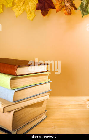Stapel alter Bücher liegt auf Holztisch auf hellen Hintergrund mit Herbst Ahorn Blätter und kopieren. Stockfoto