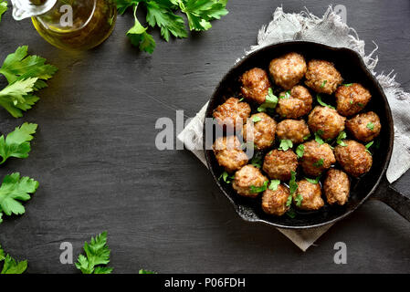 Gebratene Fleischbällchen in Pfanne bei schwarzen Stein Hintergrund. Ansicht von oben, flach Stockfoto