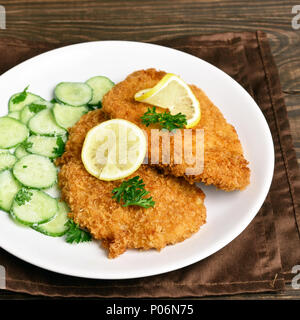 Hähnchen Schnitzel mit Gurkensalat auf weiße Platte. Nähe zu sehen. Stockfoto