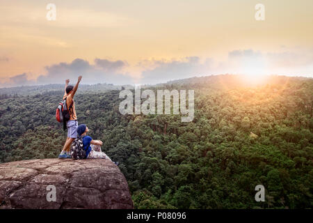 Paare von Mann und Frau auf hohe Berge mit wunderschönen sonnenuntergang himmel Hinter grünen Berg entspannen Stockfoto