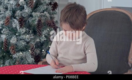 Little boy Schreiben an Santa Claus am Tisch konzentriert Stockfoto