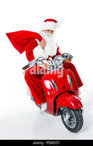 Santa Claus mit großen roten Sack sitzen auf roten Roller, isoliert auf weißem Stockfoto