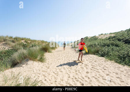 Jungen mit Surfbrettern auf Sanddünen, Camber Sands Beach, Sturz, East Sussex, England, Vereinigtes Königreich Stockfoto