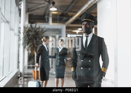 Nachdenkliche junge Piloten in Flughafen mit stewardessen vor dem Flug Stockfoto